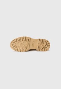 Tan rubber sole with textured grip pattern. Features Roxy logo, geometric designs, and raised accents for traction and durability.