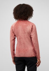 Fleecejacke in sanftem Pink mit strukturiertem, flauschigem Rücken und glatten Seitenpanelen. Mit langen Ärmeln und hohem Kragen, entworfen für Wärme.