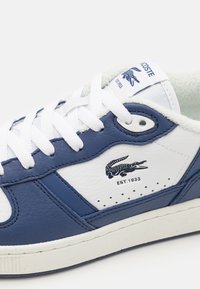 Zapatilla de cuero en navy y blanco con cordones blancos, que incluye un logo y el detalle "EST.1933" en el lateral. Textura suave, diseño clásico.