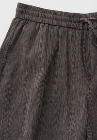 Schwarz-weiß vertikal gestreifte Hose mit elastischem Bund und Seitentaschen, mit einem auf der rechten Seite gebundenen Kordelzug.