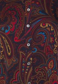 Flerfärgade paisley-skjorttyger med intrikata mönster i rött, blått och guld på en mörk bakgrund, med grå knappar längs framsidan.