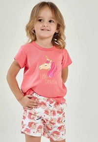 Różowy bawełniany t-shirt z grafiką jednorożca i złotym napisem, zestawiony z białymi szortami zdobionymi wzorem jednorożców i serc.