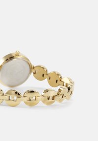 Gold-tone watch with a round case and linked band featuring oval-shaped links. Smooth texture with a polished finish. Logo engraving visible.