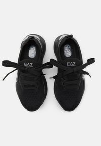 Sneakers neri in maglia con superficie testurizzata, punta rotonda e lacci neri. Presentano un'etichetta con logo e un design della suola rigata.