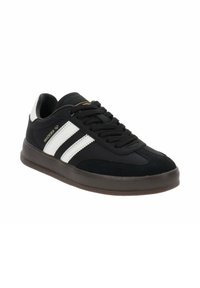 Zapatilla deportiva negra con rayas blancas, parte superior de tela y ante, punta redonda, suela texturizada y sistema de cordones. Detalle dorado en la lengüeta.