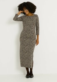 Robe longue à imprimé léopard avec manches trois-quarts, coupe ajustée et fentes latérales ; confectionnée dans un tissu doux et extensible. Chaussures plates noires ornées de clous.