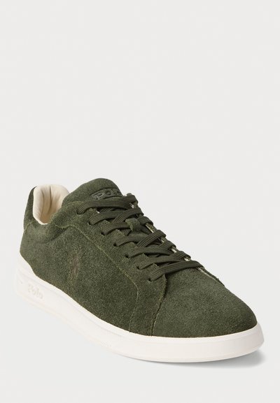 Adidași din suede verde închis cu talpă albă, design cu șireturi și un logo subtil pe lateral și pe limba încălțămintei, inclinați pentru a arăta vederea exterioară și frontală.