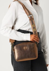 Borsa a tracolla in metallo bronzeo con logo, finitura testurizzata e tracolla regolabile a fantasia. Forma rettangolare compatta, adatta per l'uso quotidiano.