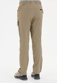 Pantalons d'extérieur beiges avec une taille extensible, des poches zippées et des poignets ajustables, fabriqués dans un tissu durable et léger.
