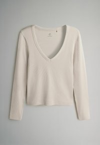 Maglietta a maniche lunghe con scollo a V realizzata in tessuto a coste di colore crema. Design semplice con una vestibilità rilassata e senza hardware o motivi visibili.