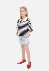 Camisa polo a rayas azul marino y blanca con cuello blanco, combinada con una falda de mezclilla azul clara y bailarinas de cuero rojas.