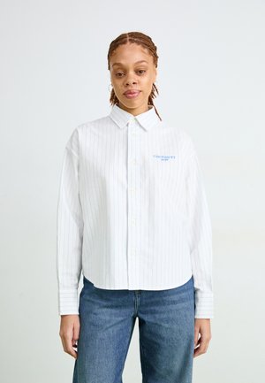 Camicia bianca con righe verticali blu, dotata di un piccolo logo blu sul petto e maniche lunghe, abbinata a jeans blu.