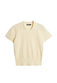 Vaaleankeltainen lyhythihainen pooloneule, jossa on V-kaula-aukko ja valkoinen kontrastikaulus, valmistettu pehmeästä neuloksemateriaalista, jossa hienovarainen logoyksityiskohta.