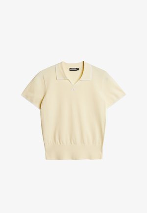 Kortærmet polo i lysegul med v-hals og hvid kontrastkrave, lavet af blødt strikmateriale med diskret logodetalje.