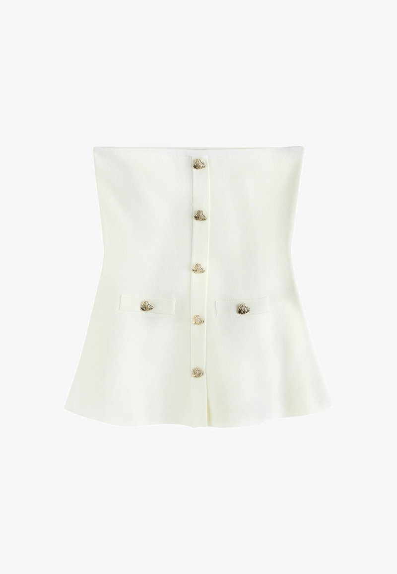 Haut blanc sans bretelles avec fermeture à boutons sur le devant et deux petites poches avant, chacune ornée de boutons décoratifs dorés en forme de coquillage.