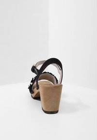 Sandali con tacco in suede nero, con tacco a blocco in legno, cinturino alla caviglia regolabile e decorazioni sul lato superiore.