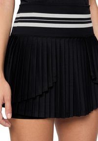 Gonna plissettata nera con una ampia cintura testurizzata caratterizzata da due strisce bianche orizzontali. Il tessuto è liscio con elementi di design a strati.