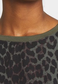 Leopard-patterned fabric in dark gray and black, featuring a smooth texture, rounded green ribbed neckline, and subtle sheen.