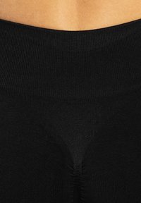 Leggings noirs extensibles à côtes avec une taille haute, présentant une texture lisse et un design ajusté sans coutures visibles.