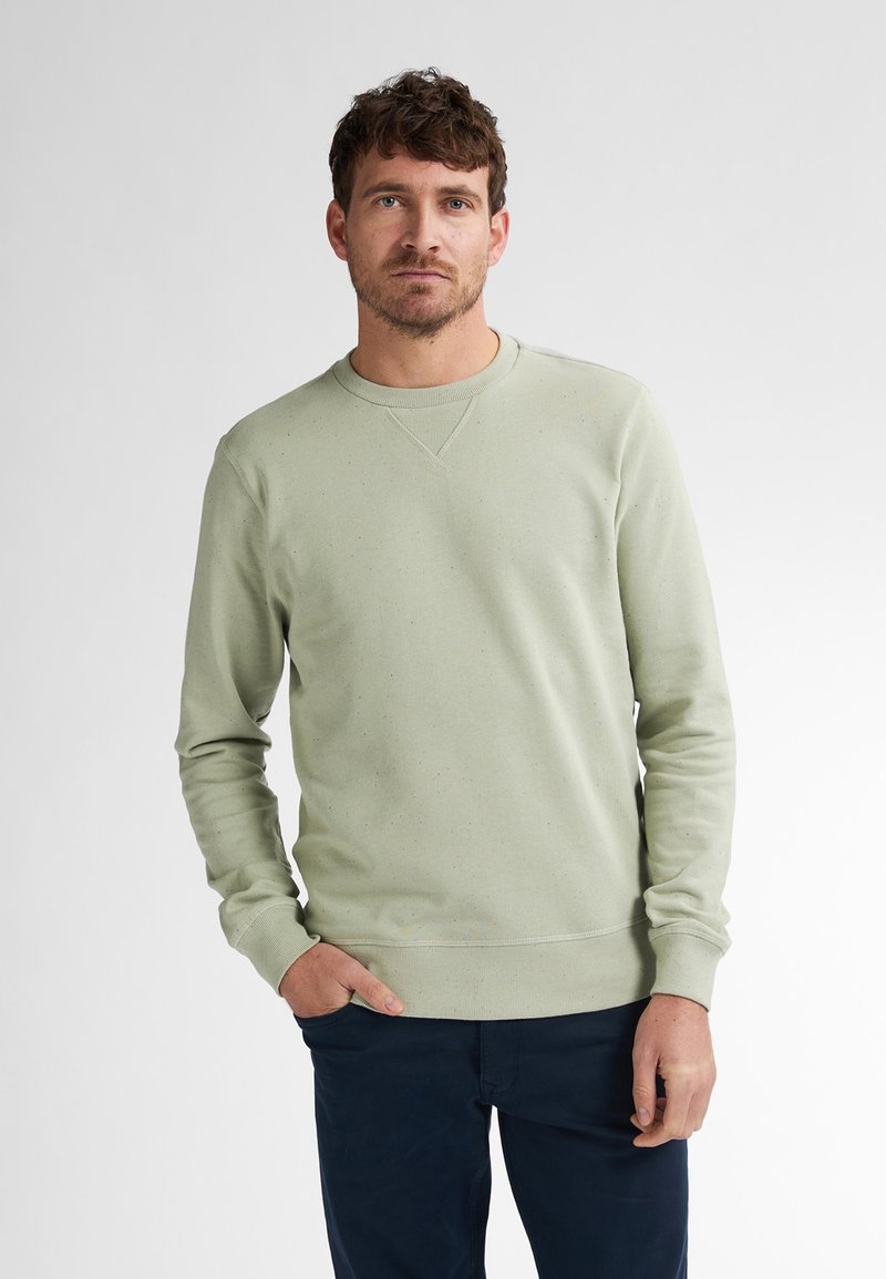 Sudadera verde claro con cuello redondo, que presenta una tela texturizada y un detalle salpicado mínimo. Manga larga y puños de canalé.