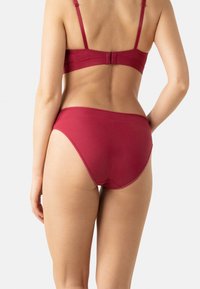 Sous-vêtements rouges, sans couture, avec une texture lisse et un design taille haute, dotés d'une simple ceinture élastique et d'un minimum de détails.