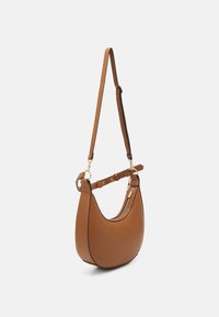 Sac à bandoulière en cuir marron en forme de croissant avec une sangle ajustable et des détails en zip doré sur fond blanc.