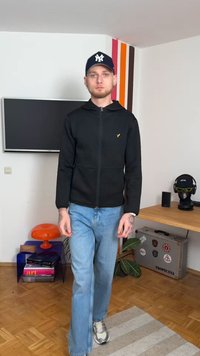 Must kapuutsiga lõhikutega dressipluus tekstuurse kangaga, millel on väike kollane logo. Valmistatud helesinistest teksadest ja hallidest tennistest.