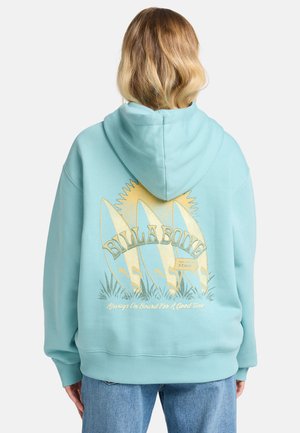 Turquoise hoodie met een grafisch ontwerp op de achterkant, featuring surfplanken en de tekst "BILLA BONG" in donkergroen en goud.