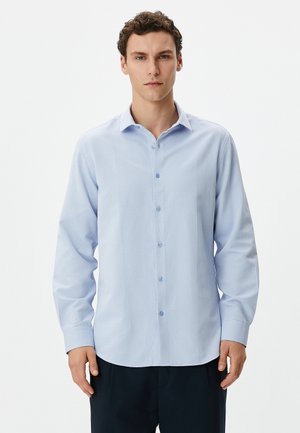 Camisa de botón de manga larga en azul claro con un patrón texturizado, que presenta un cuello clásico y botones en azul claro. Corte ajustado.