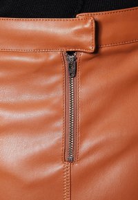 Brun läderskjol med en central metallblixtlås, slät textur och sydda detaljer längs midjan för extra design.