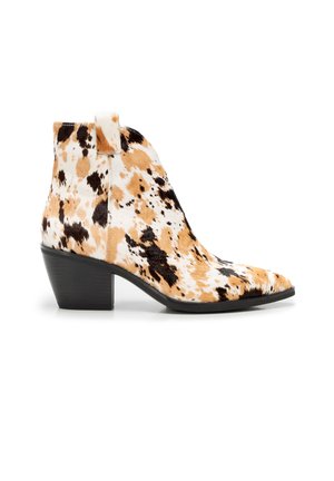 Bottine montant à la cheville avec motif peau de vache noire, marron et blanc, bout pointu et talon moyen épais noir.