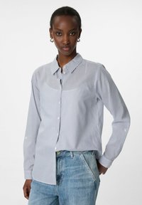 Hemd mit Knopfleiste in hellblau und weißen vertikalen Streifen, mit Kragen, langen Ärmeln und entspannter Passform. Kombiniert mit hellblauen Jeans.