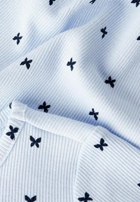 Tissu tissé bleu clair avec des côtes, présentant des motifs de papillons noirs brodés partout. Comprend un détail de poignet texturé.