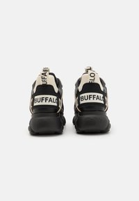 Fekete és bézs sportcipők tömzsi talpával, kiemelkedő "BUFFALO" márkajelzéssel a saroknál és húzófülekkel a könnyű felvétel érdekében.