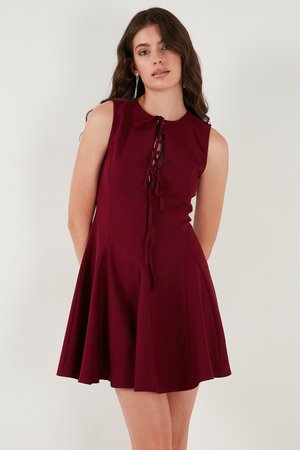 Burgundy sleeveless dress, featuring a lace-up front, flared skirt, and smooth texture. Designed to fit comfortably at the waist.