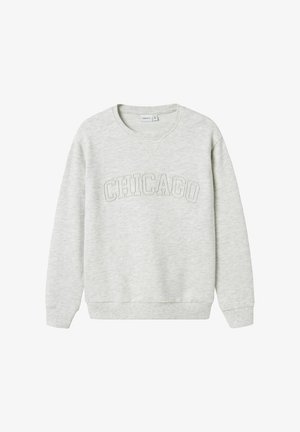 Svetlo siva dukserica iz mekog materijala s teksturiranim grafičkim natpisom "CHICAGO" preko grudi. Rebrasti rubovi na rukavima i donjem delu. Klasičan okrugli izrez.