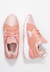 Zapatillas deportivas rosas con una mezcla de materiales de satén y malla, que cuentan con una correa texturizada, puntera redondeada y suela de goma blanca.