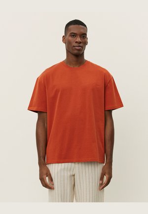 Rust-colored short-sleeve T-shirt in cotton with a round neckline, relaxed fit, and subtle embroidered detail on the left chest.