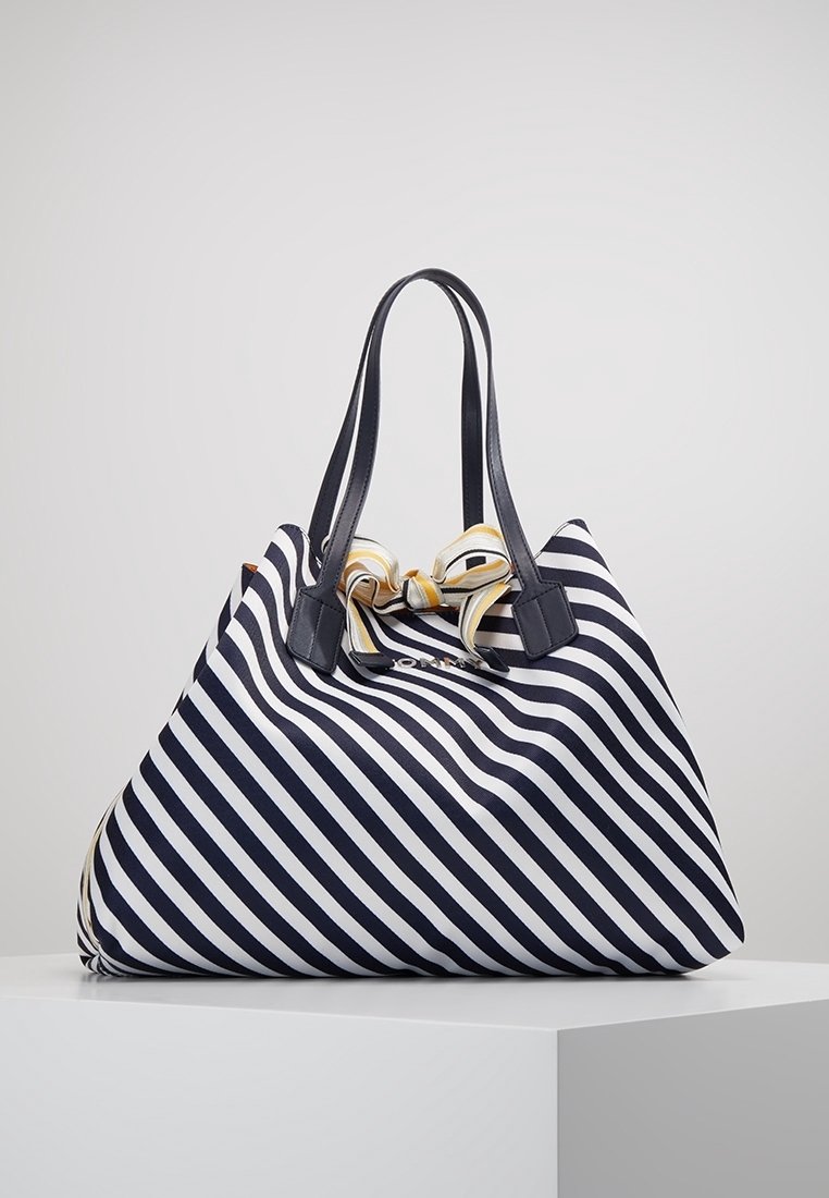 Borsa a tracolla a righe diagonali blu navy e bianche con manici neri e un fiocco a righe giallo e bianco legato in cima.