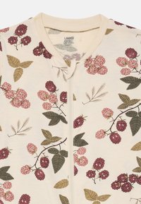 Zipfel-Overall aus weichem cremefarbenem Stoff, mit einem Himbeer- und Blattmuster in Rosa-, Rot- und Grüntönen. Schlichter Kragen.
