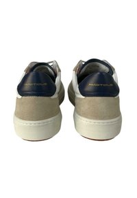 Sneakers in suede beige con suole in gomma bianche e tallone in pelle blu navy. "AMBITIONOUS" è impresso in oro sulla parte posteriore.