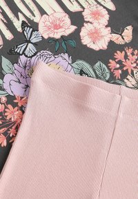 T-shirt in cotone con base grigio scuro, caratterizzato da stampe floreali e di farfalle in rosa e verde. Leggings leggeri rosa chiaro con una texture morbida.