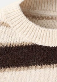 Suéter de punto en color crema con rayas marrones y beige. Presenta un cuello acanalado y una textura suave, destacando los colores contrastantes.