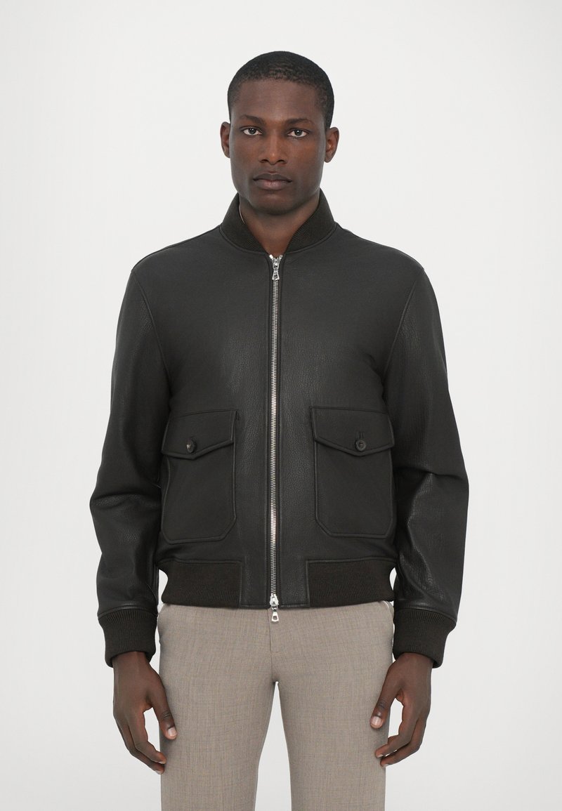 Chaqueta bomber de cuero negro con cierre frontal de cremallera, puños acanalados y dos bolsillos en el pecho. Material texturizado, diseño aerodinámico.
