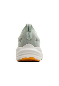 Chaussure de sport vert clair avec une tige texturée, une languette de traction, une semelle intermédiaire blanche lisse et une semelle en caoutchouc orange. Présente un design minimaliste.