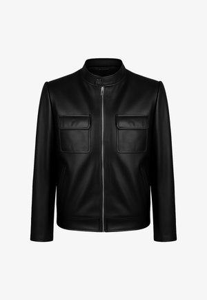 Black leather jacket with a stand collar, front zipper, and two chest pockets. Smooth texture with subtle stitching and tailored fit.