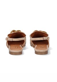 Sandalias beige con una plantilla marrón texturizada, tiras delgadas y un hebilla en la parte trasera. La suela presenta un diseño plano para mayor comodidad.