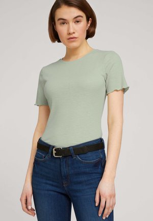 T-shirt vert clair à rayures, avec des manches courtes à bords festonnés, associé à un jean bleu marine et une ceinture noire avec une boucle en argent.