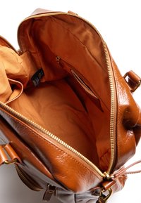 Borsa in pelle marrone con chiusura a zip, dotata di un ampio interno in tessuto arancione, una tasca interna con zip e un'etichetta all'interno.