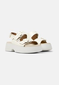 Bílé kožené platformové sandály s dvěma nastavitelnými přezkami, zaoblenou špičkou a texturovanou podrážkou pro lepší grip.